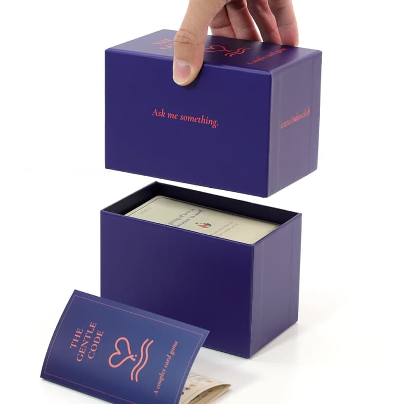 Hand opening The Gentle Code game box revealing conversation cards inside
